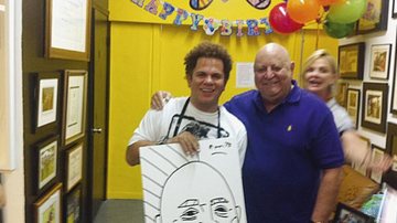 Romero Britto comemora 48 anos ao lado do amigo Luiz Schmidt, que completa 69 anos e ganha desenho de seu rosto assinado pelo artista, na galeria de Britto, em Miami.