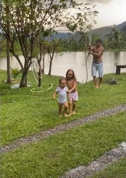 Rafael Cardoso toma banho de chuva com os filhos