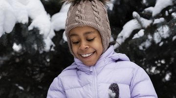 Criança brincando na neve durante o inverno - Foto: Freepik