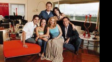 O casal com os filhos Amaury e Maria Eduarda, com o genro Alexandre e a nora Fernanda, na sala de estar com móveis em tons escuros e fortes, como o preto e o laranja.
