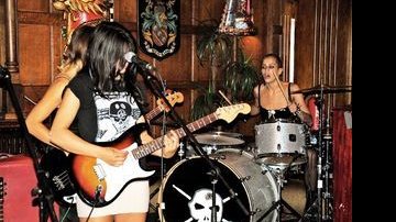 Com sua banda, ela toca bateria no White Trash Fast Food com o visual que a marca: cabelo raspado do lado, vestido curto e transparente e acessórios punk-rock. - Queen International