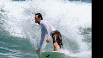 O ator desliza em uma onda na praia da Macumba, Rio, e exibe abdômen e braços mais malhados.