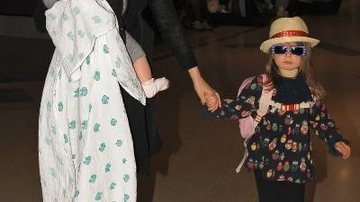 Estilosa de óculos de sol, chapéu e mochila, Olive, a primogênita da atriz e escritora, caminha de mãos dadas com sua famosa mãe, que leva no colo a caçula, Elula, por aeroporto da Big Apple. - SPLASH NEWS