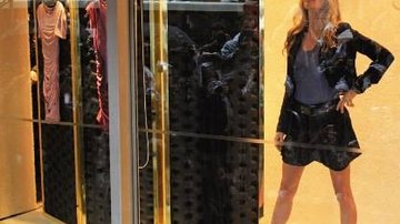 Com blusa azul e saia e casaco pretos com cinto e sapatos da mesma cor, a übermodel exibe peças assinadas por ela em shopping em São Paulo. - REUTERS