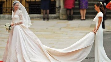 Kate encanta com o longo de renda e seda. Pippa segura a cauda ricamente bordada. - Reuters