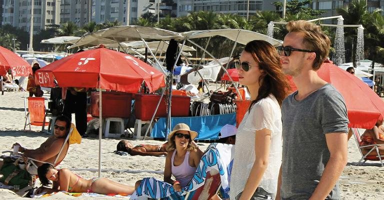 O ator inglês que faz o vilão Draco Malfoy nos filmes da saga Harry Potter vai de calça à praia de Copacabana com a namorada, Jade. - GABRIEL REIS E AGNEWS