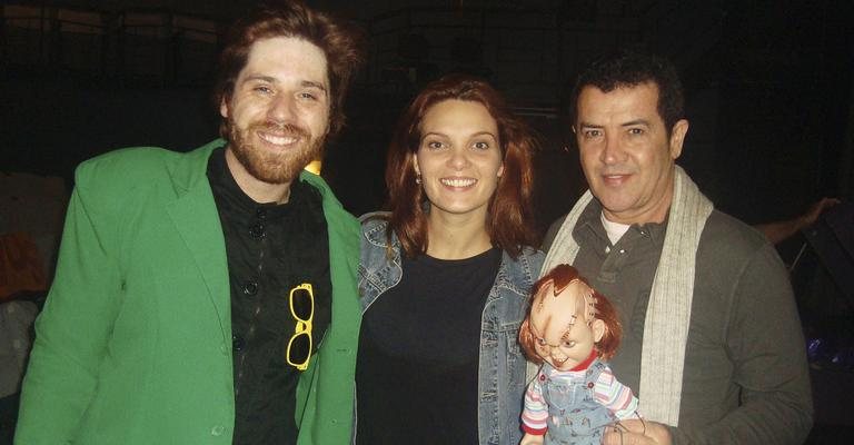 Em SP, Pedro Monteiro e Thábata Tubino aplaudidos por Beto Barbosa, com o boneco Chucky, que compõe o cenário.