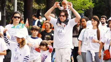 Com sua pequena Ella nos ombros e o filho João ao seu lado, Fabio faz caminhada solidária. - AgNews