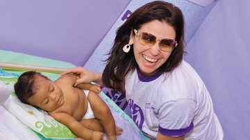 Sorridente, Giovanna mima bebê durante o lançamento de Prematuro Imunizado é Prematuro Protegido. - -