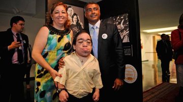 Regina Próspero, com o filho Dudu, e o deputado Romário conferem a mostra fotográfica sobre a doença mucopolissacaridose, no DF. - -