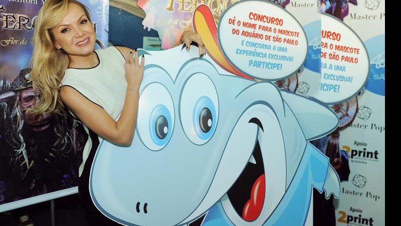 Eliana posa para foto atrás de cartaz de mascote - Francisco Cepeda e Thiago Duran / AgNews