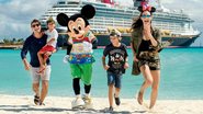 O casal e os filhos Artur, no colo do pai, e Lucas, são recebidos por Mickey na Castaway Cay - CHLOE RICE