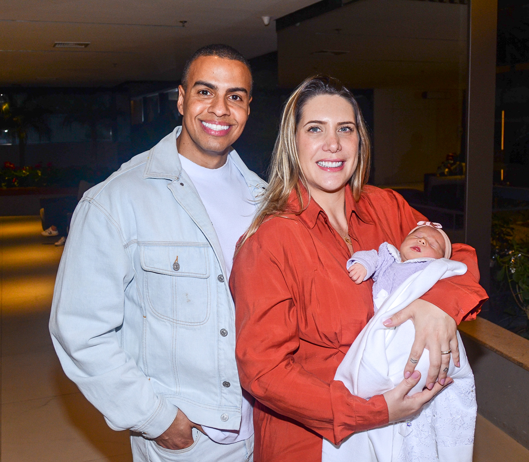 Thiago Oliveira é fotografado com Bruna Matuti e a filha, Ella, na saída da maternidade