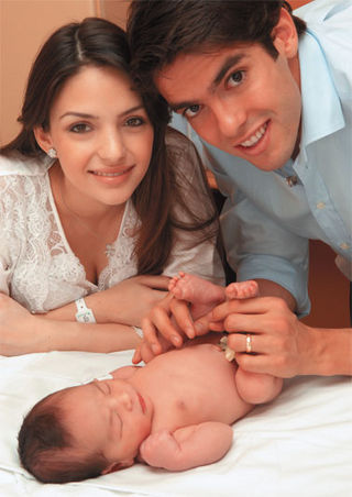 Encantados com o filho recém-nascido, o jovem casal cerca o pequeno de ca