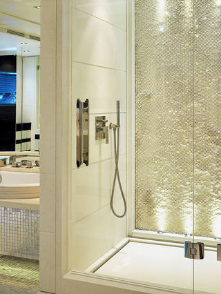 Apesar do ar clássico, uma parede de lantejoulas no box do chuveiro é a surpresa no banheiro do casal