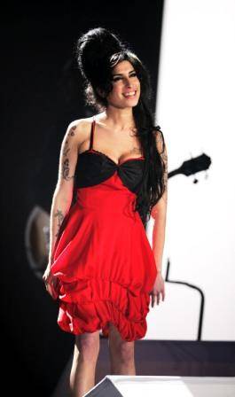 Durante um de seus shows, Amy Winehouse usa vestido um pouco mais comportado, que a deixa muito elegante