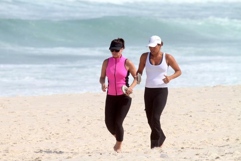 Giovanna Antonelli corre ao lado de amiga na praia da Barra da Tijuca