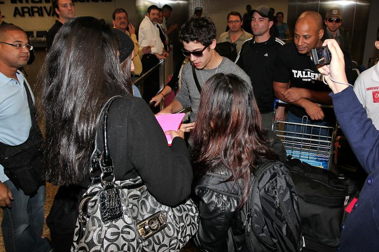 Nick Jonas dá autógrafos a fãs ao chegar no aeroporto de Guarulhos, em São Paulo