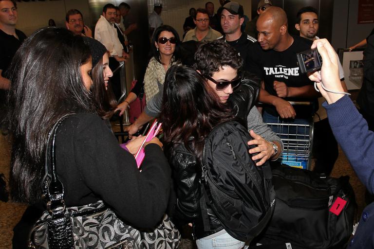 Nick Jonas abraça fã que o recepciona no aeroporto de Guarulhos, em São Paulo