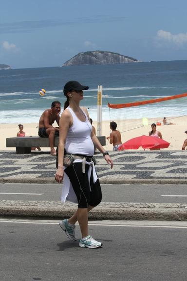 Grávida, Lavínia Vlasak caminha pela orla da praia do Leblon, no Rio de Janeiro