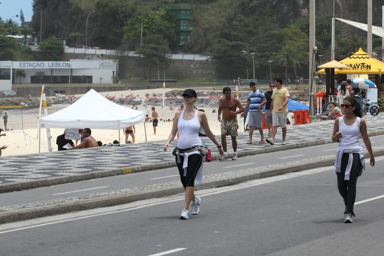 Grávida, Lavínia Vlasak caminha pela orla da praia do Leblon, no Rio de Janeiro