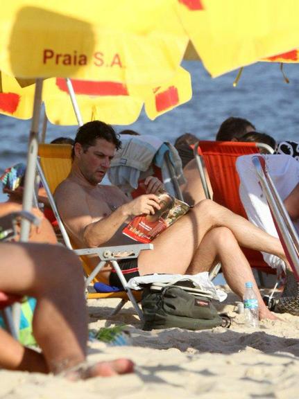 Marcelo Serrado toma banho de mar e lê na praia