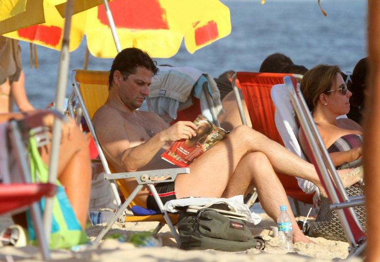 Marcelo Serrado toma banho de mar e lê na praia