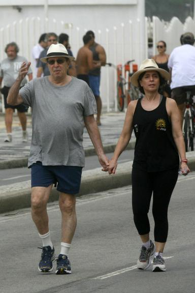 Daniel Filho caminha com a mulher, Olivia Byington, pela orla da praia de Ipanema