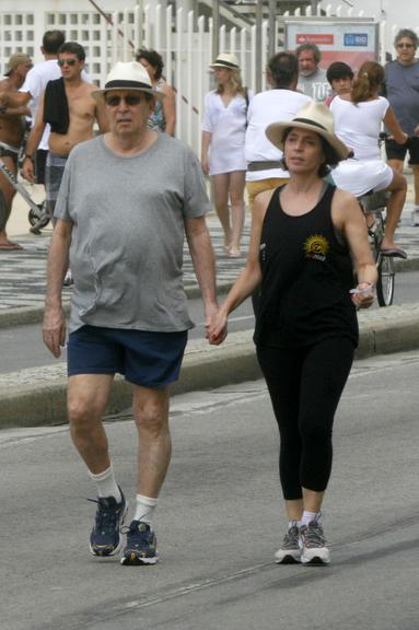 Daniel Filho caminha com a mulher, Olivia Byington, pela orla da praia de Ipanema
