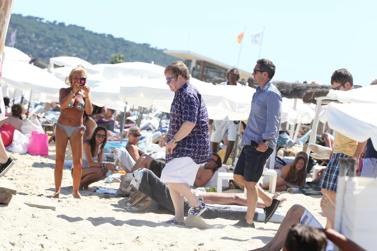 Com camisa e tênis estampados, Elton John passeia pelo litoral da França