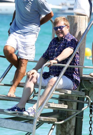 Com camisa e tênis estampados, Elton John passeia pelo litoral da França