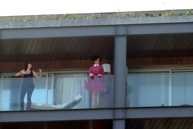 De rosa e contra o vento, Katy Perry acena para os fãs de varanda de hotel no Rio de Janeiro 