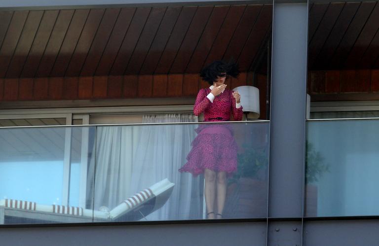 De rosa e contra o vento, Katy Perry acena para os fãs de varanda de hotel no Rio de Janeiro 