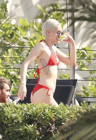 Miley Cyrus beija rapaz durante dia de folga na piscina