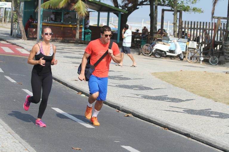 Enzo Celulari corre com a namorada em orla da praia no Rio
