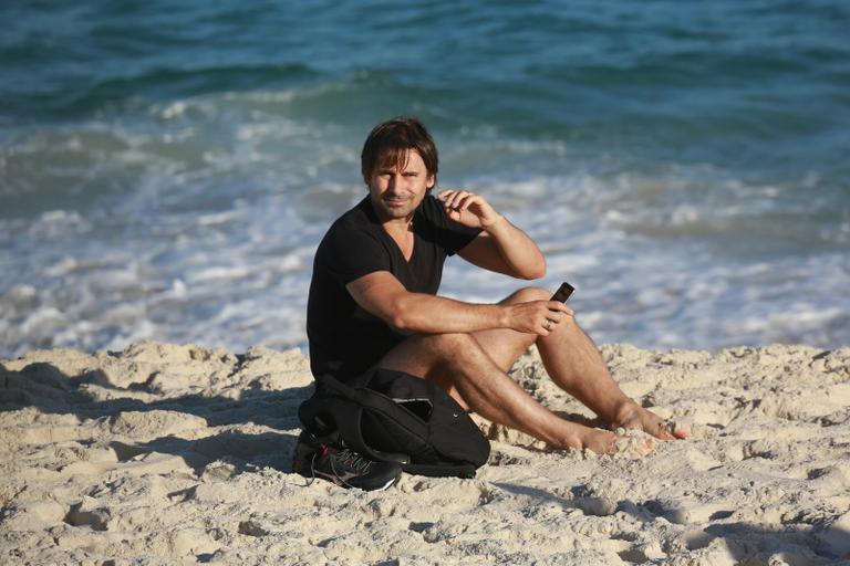 Sem desgrudar do celular, Murilo Rosa curte dia de praia no Rio de Janeiro