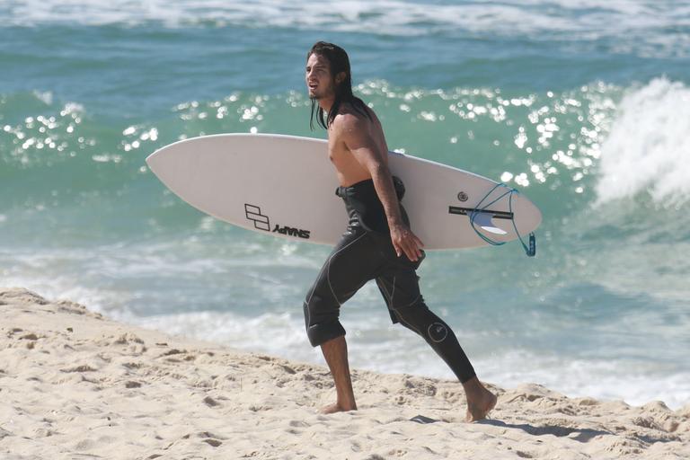 De cabelo solto, Tiago Iorc surfa no Rio e exibe boa forma ao trocar de roupa na rua