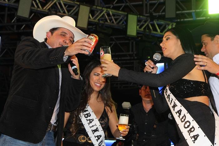 Simone e Simaria brindando com copo de cerveja no palco do evento