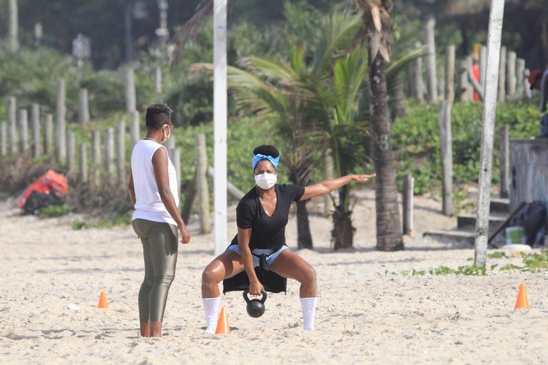De máscara, Adriana Bombom treina na praia